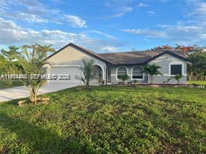 A single-story house with a gray exterior, a two-car garage, and a grassy front yard — 15854 Tangelo Blvd, Loxahatchee FL 33412, LOXAHATCHEE, FL