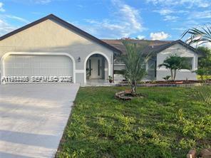 A single-story house with a two-car garage, arched entryway, and a grassy front yard — 15854 Tangelo Blvd, Loxahatchee FL 33412, LOXAHATCHEE, FL