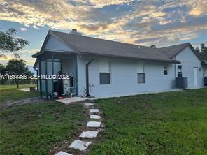 The exterior of a single-story house with a screened porch and a stone walkway — 15854 Tangelo Blvd, Loxahatchee FL 33412, LOXAHATCHEE, FL