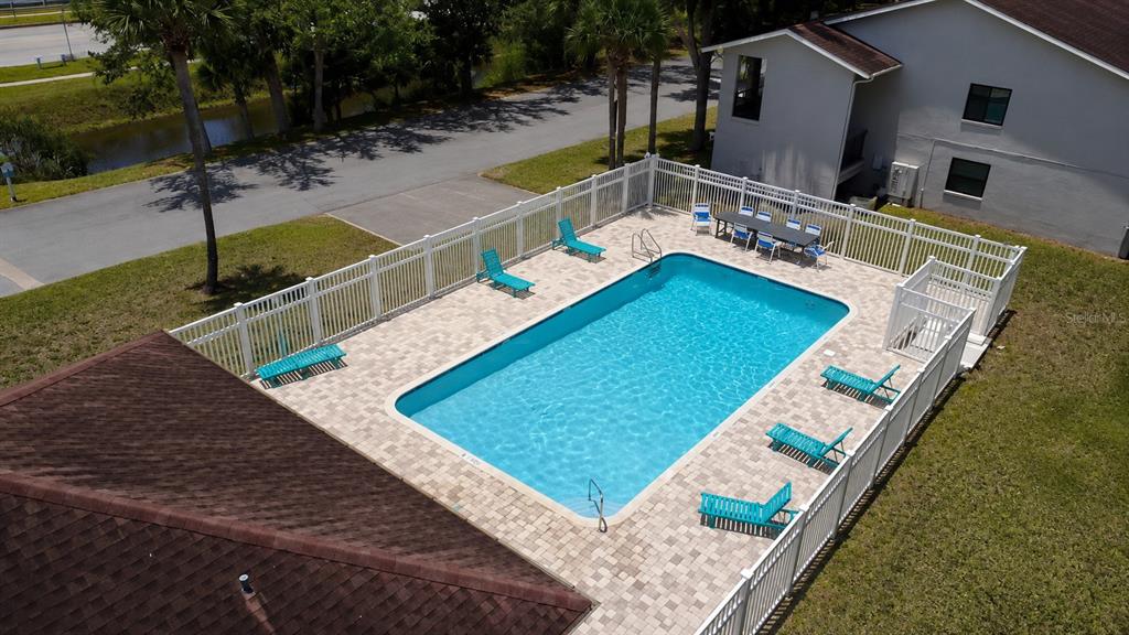 An aerial view shows a rectangular swimming pool surrounded by a paved deck and white fencing — 2275 62ND AVENUE N UNIT 5202, ST PETERSBURG, FL