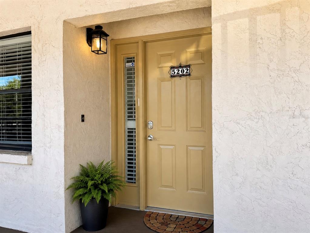 A tan front door with a side window and house number 5202 under a light — 2275 62ND AVENUE N UNIT 5202, ST PETERSBURG, FL