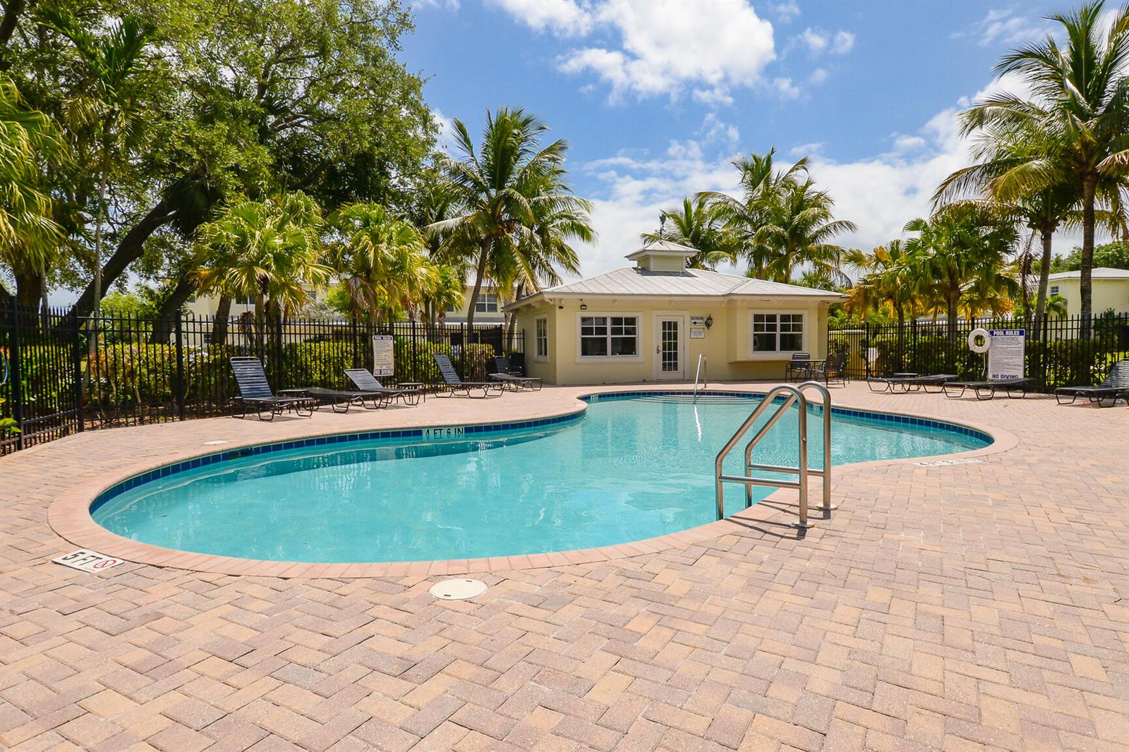 A swimming pool with a surrounding brick patio and a small clubhouse in the background — 3904 Sabal Way, Fort Pierce FL 34981, FORT PIERCE, FL