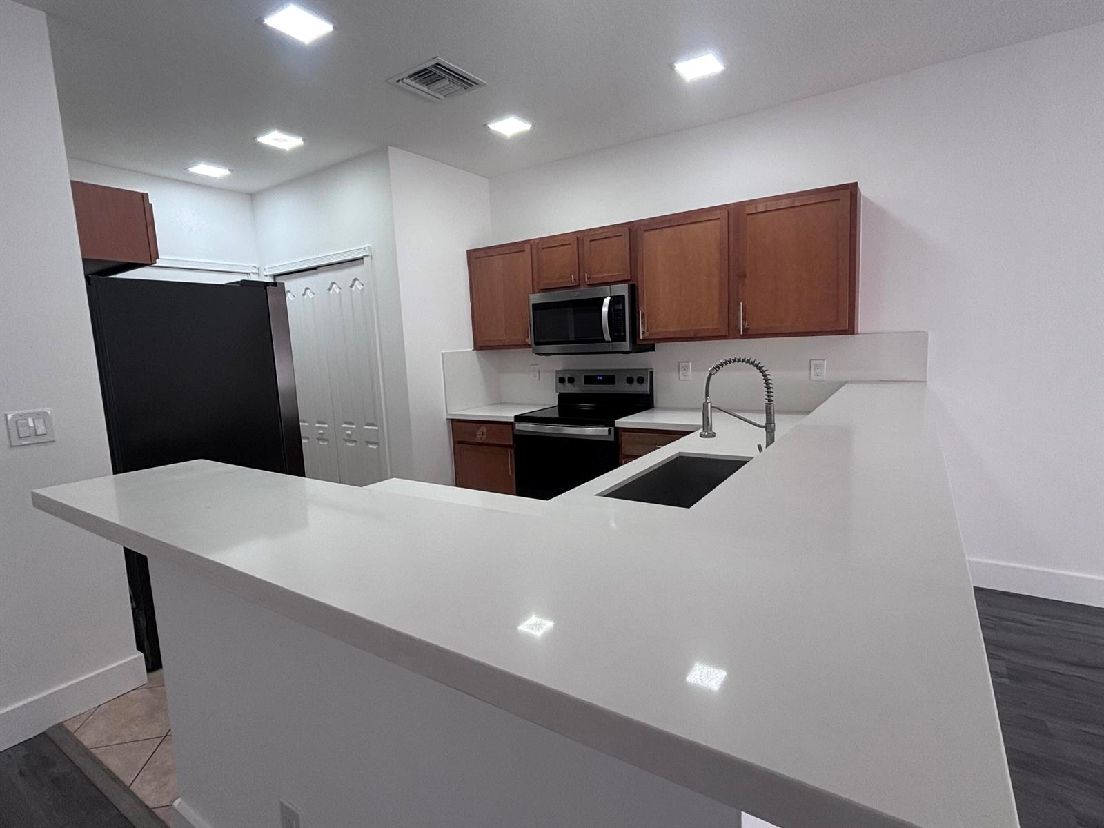 A kitchen features white countertops, wooden cabinets, black appliances, and recessed lighting — 3904 Sabal Way, Fort Pierce FL 34981, FORT PIERCE, FL