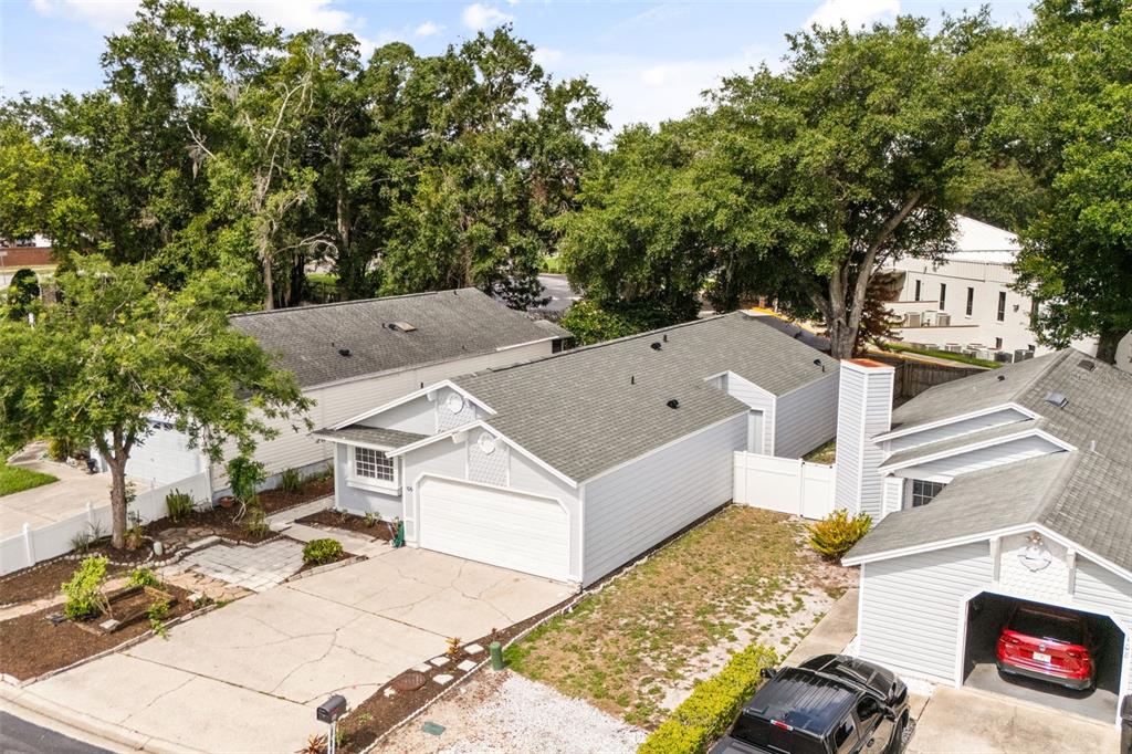 An aerial view shows three light-colored suburban houses with driveways and mature trees — 106 LAMPLIGHTER DRIVE, SANFORD, FL