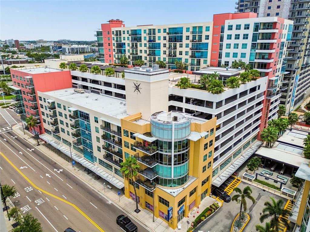 An aerial view shows a multi-story apartment complex with a parking garage and palm trees — 1120 E KENNEDY BOULEVARD UNIT 1030, TAMPA, FL