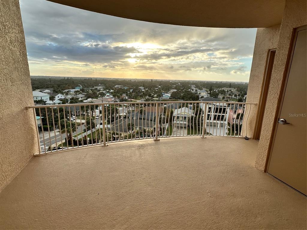 A high-rise balcony with a metal railing overlooks a residential neighborhood at sunset — 711 S ATLANTIC AVENUE UNIT 701, NEW SMYRNA BEACH, FL