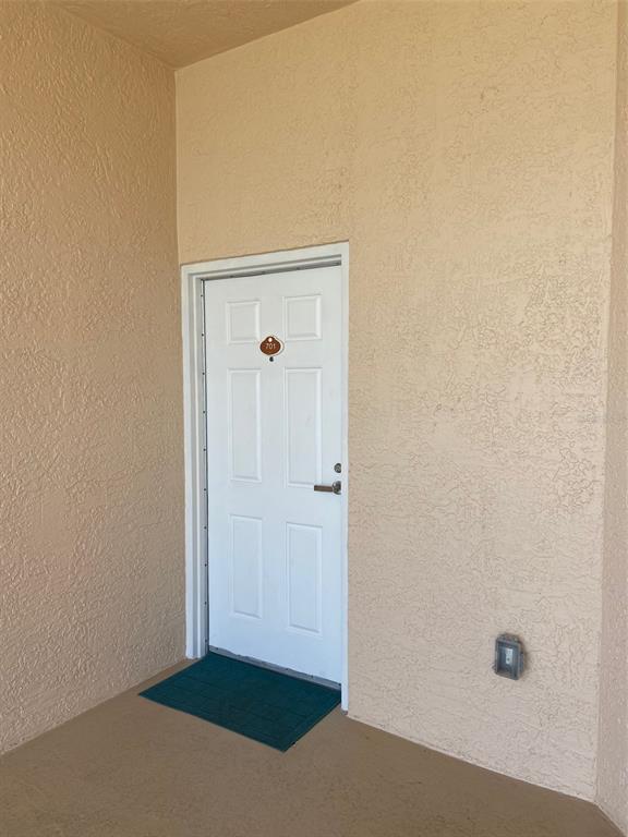 A white six-panel door with a room number sign is set into a textured beige wall — 711 S ATLANTIC AVENUE UNIT 701, NEW SMYRNA BEACH, FL