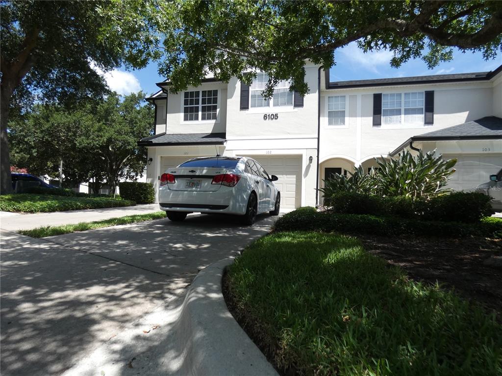 A white sedan is parked in the driveway of a two-story townhouse with white siding — 6105 TWAIN STREET UNIT 102, ORLANDO, FL