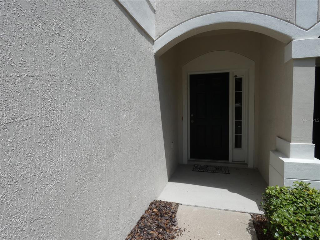 A dark front door with a sidelight is recessed under an arched entryway — 6105 TWAIN STREET UNIT 102, ORLANDO, FL