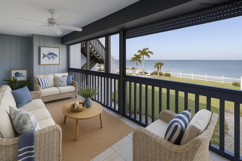 A covered porch with wicker furniture overlooks a grassy lawn and the ocean — 812 BAHIA DEL SOL DRIVE UNIT A, RUSKIN, FL