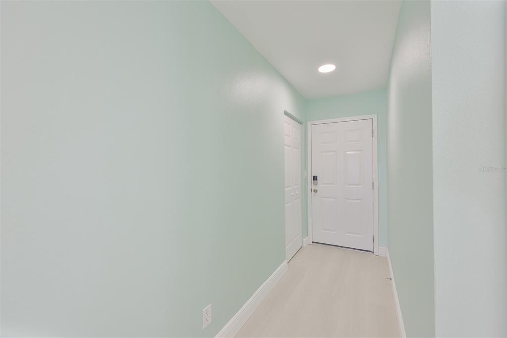 A hallway with light green walls, white trim, and a white door — 812 BAHIA DEL SOL DRIVE UNIT A, RUSKIN, FL