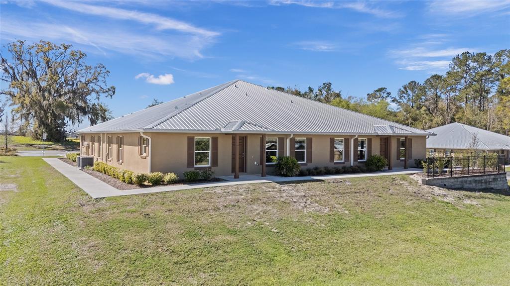 A tan, single-story building with a metal roof sits on a grassy, sloped lot — 4415 NW 74TH TERRACE, OCALA, FL