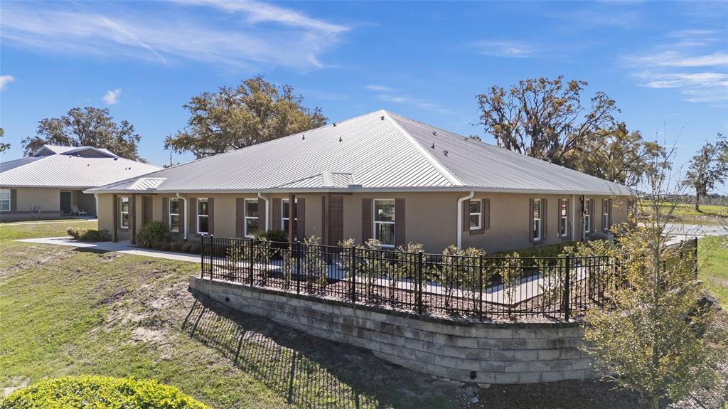 A tan single-story building with a metal roof sits behind a black metal fence — 4415 NW 74TH TERRACE, OCALA, FL