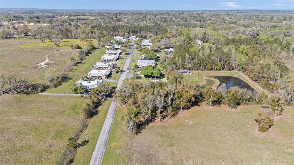 An aerial view shows a residential street lined with houses surrounded by fields and trees — 4415 NW 74TH TERRACE, OCALA, FL