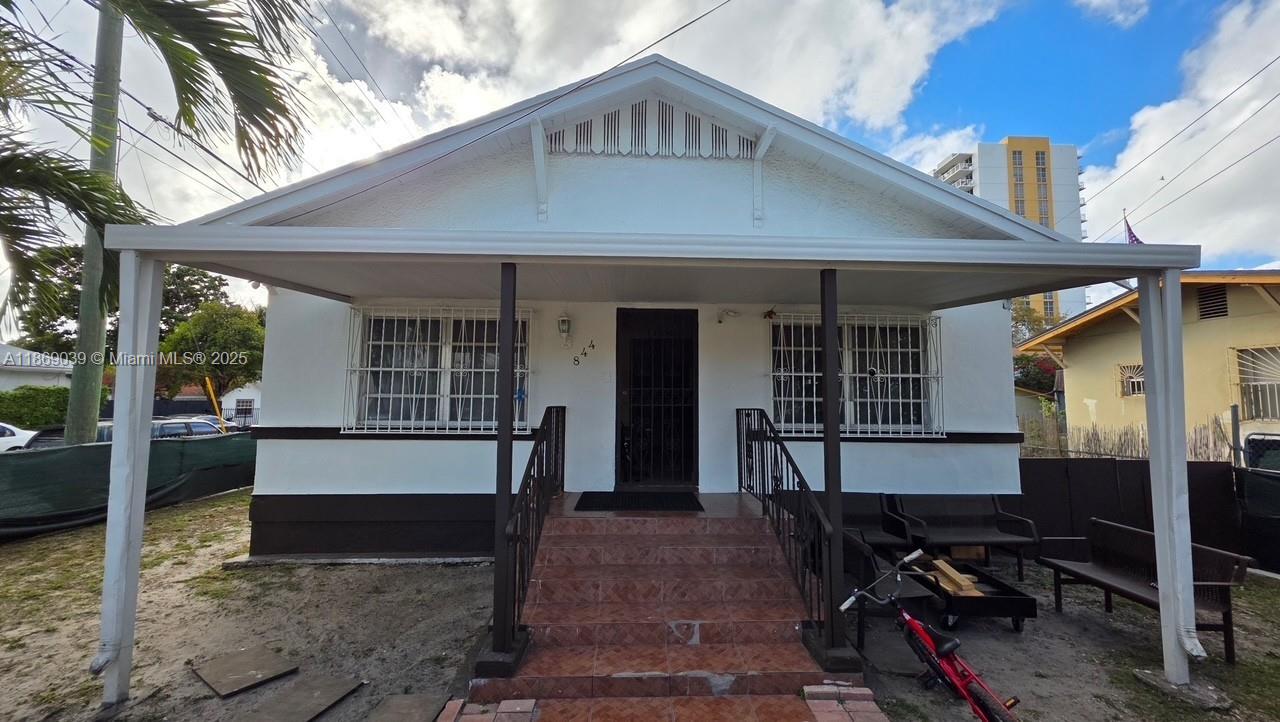 A white single-story house features a front porch with steps and metal security window bars — 844 SW 8th Ct, Miami FL 33130, MIAMI, FL
