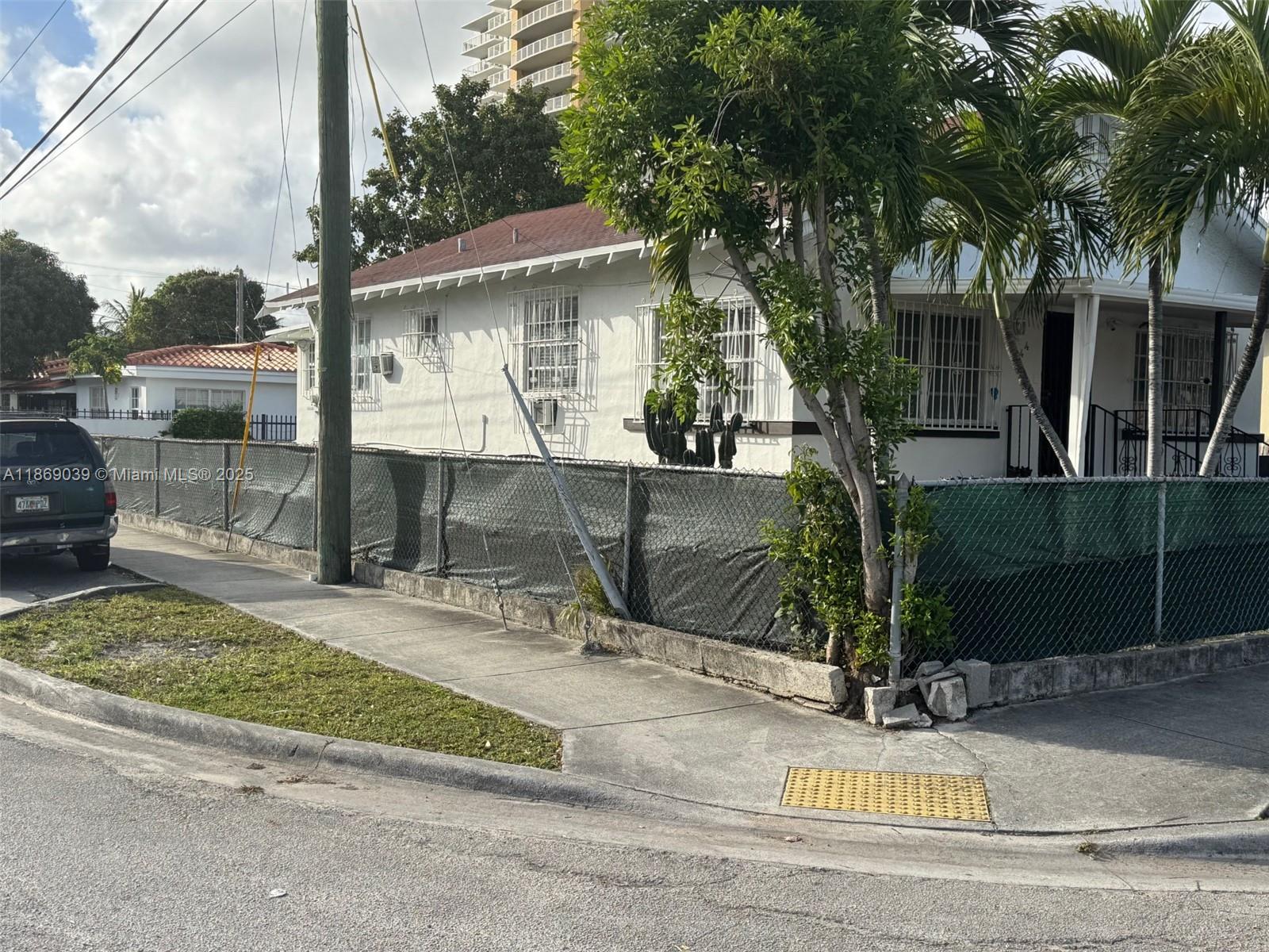 A white house with a chain-link fence and palm trees sits on a corner lot — 844 SW 8th Ct, Miami FL 33130, MIAMI, FL