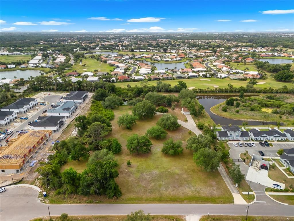 An aerial view shows a vacant, tree-covered lot situated between residential developments and a golf course — 2900 CURRY LANE, NOKOMIS, FL