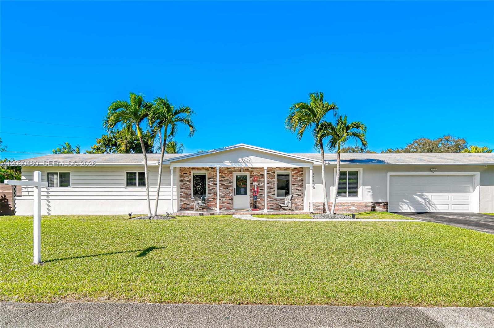 A single-story house features a brick facade, white siding, a two-car garage, and palm trees — 10600 SW 80th Ct, Miami FL 33156, MIAMI, FL