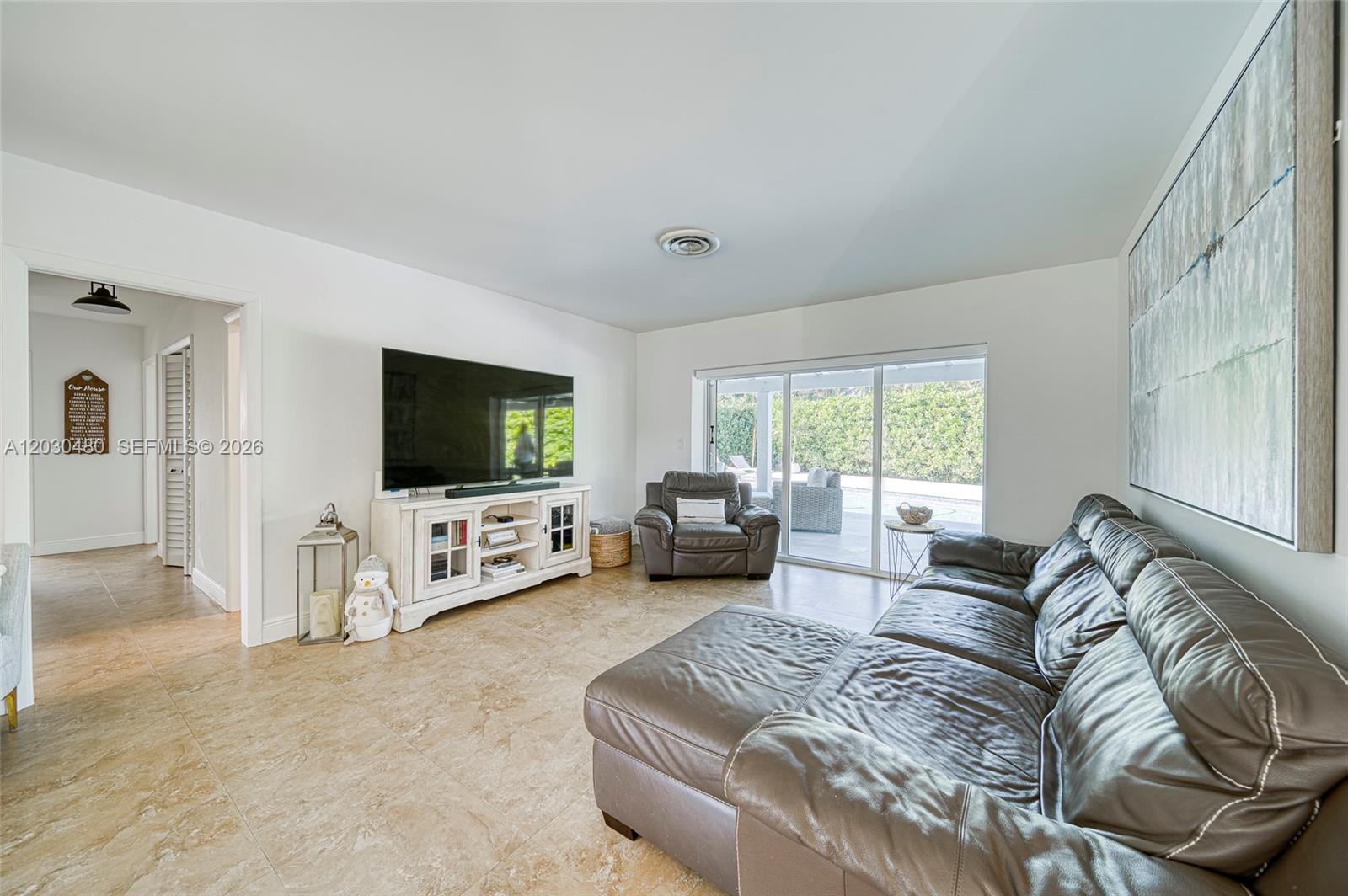 A living room features tile flooring, a leather sectional, a television console, and sliding doors — 10600 SW 80th Ct, Miami FL 33156, MIAMI, FL
