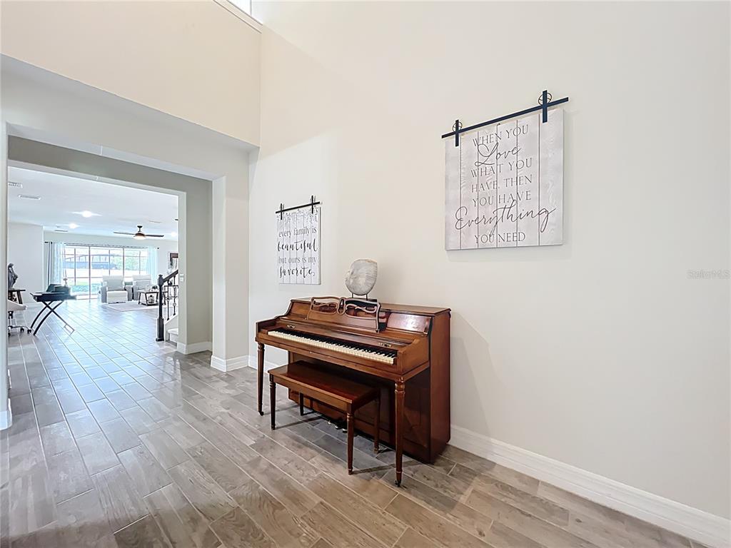 A wooden piano sits against a wall in a room with tiled floors — 15084 CUDDY COURT, ORLANDO, FL