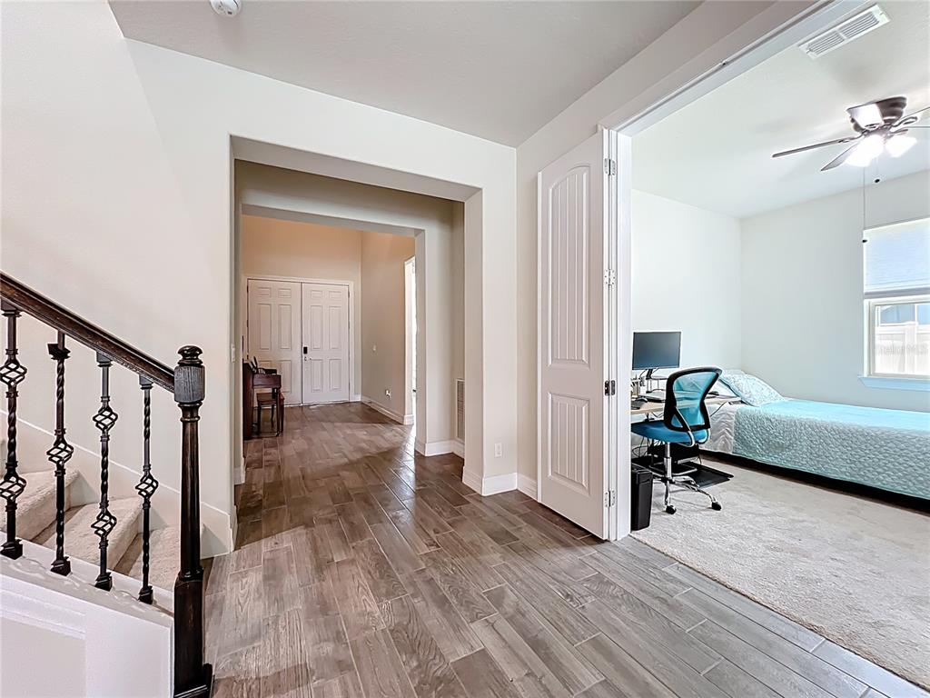 A view of a home interior featuring a staircase, tiled flooring, and a bedroom office — 15084 CUDDY COURT, ORLANDO, FL