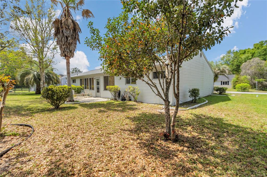 The exterior of a single-story house with light siding and a backyard patio — 10841 SW 90TH COURT, OCALA, FL