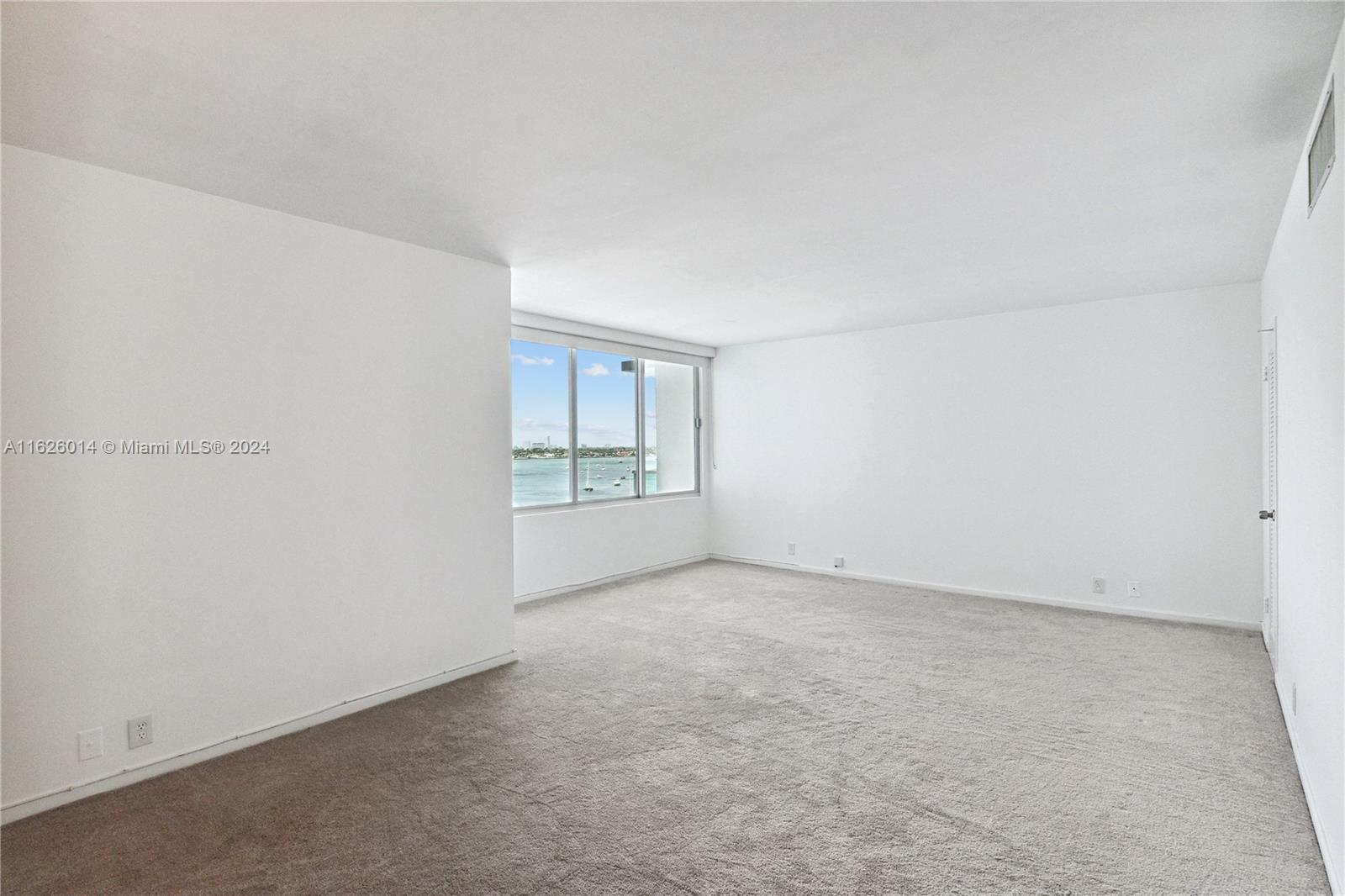 An empty room with white walls, beige carpeting, and a window overlooking the water — 1000 West Ave # 821, Miami Beach FL 33139, MIAMI BEACH, FL