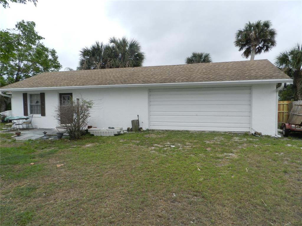 A white house exterior features a large garage door, a side entrance, and a small patio — 805 OCEAN AVENUE, NEW SMYRNA BEACH, FL