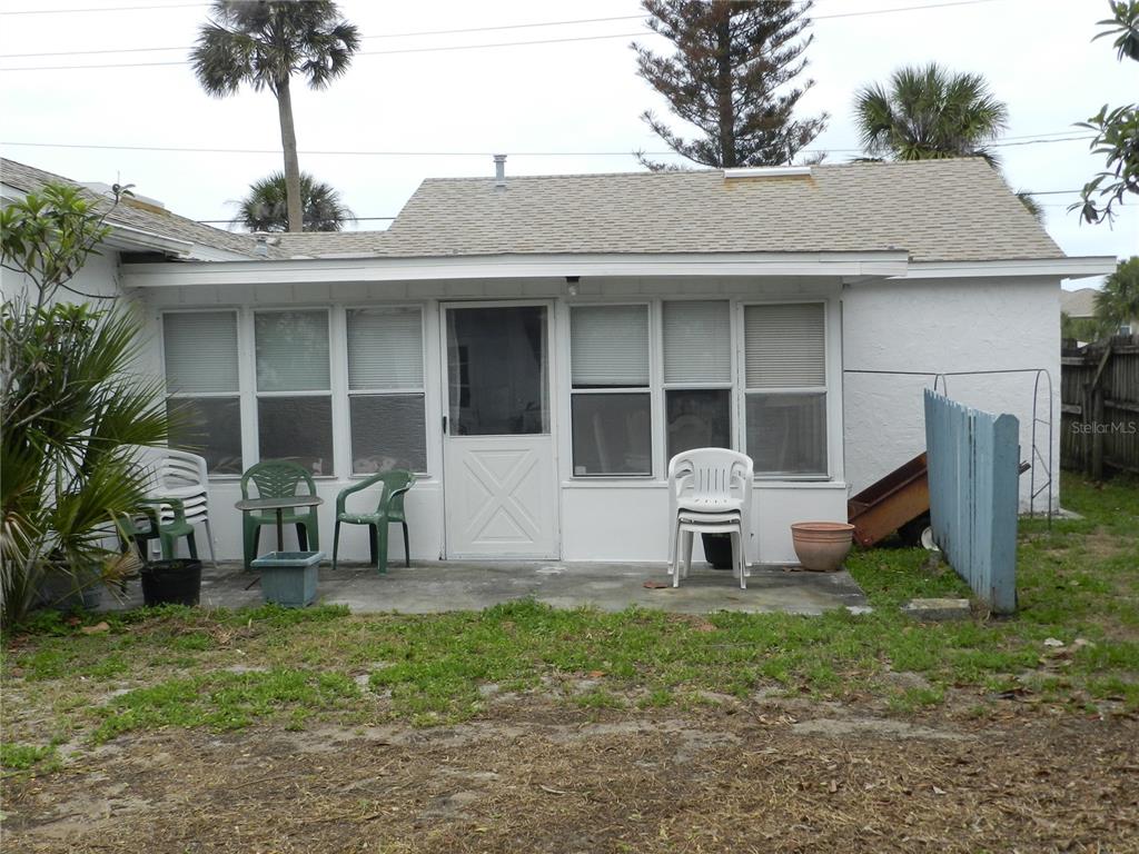 A white house exterior features a screened-in porch with a concrete patio and lawn — 805 OCEAN AVENUE, NEW SMYRNA BEACH, FL