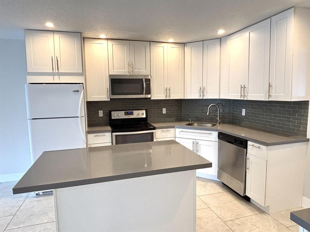 A kitchen features white cabinets, gray countertops, a gray tile backsplash, and stainless steel appliances — 3851 NW 84th Avenue # 1a, Sunrise FL 33351, SUNRISE, FL