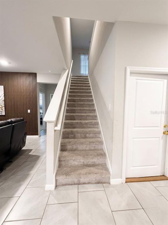 A carpeted staircase leads to an upper level next to a white door and tiled floor — 3817 SUNNY SPRING STREET, PLANT CITY, FL