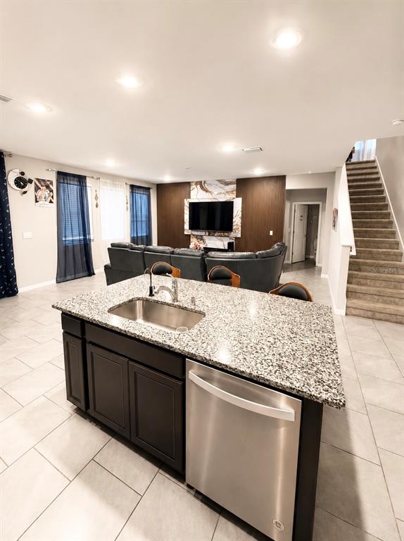 A kitchen island with a granite countertop and stainless steel dishwasher faces a living area — 3817 SUNNY SPRING STREET, PLANT CITY, FL