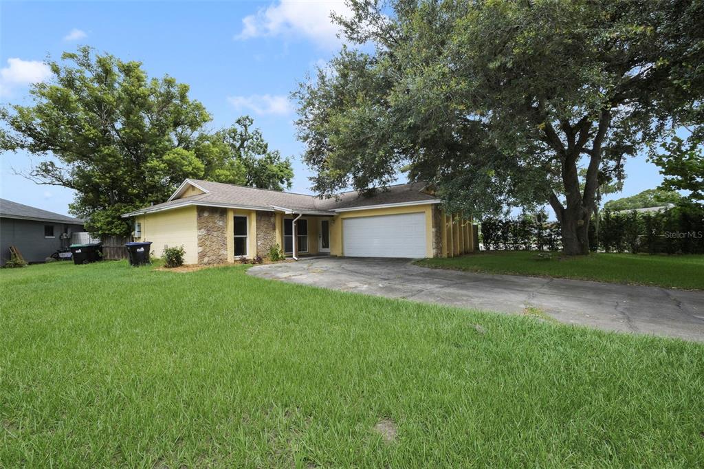 A single-story house with yellow siding, stone accents, and a two-car garage — 1530 RAVANA DRIVE, ORLANDO, FL