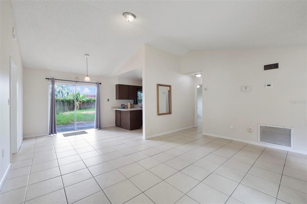 An open-concept living area features light tile flooring, a vaulted ceiling, and a sliding glass door — 1530 RAVANA DRIVE, ORLANDO, FL