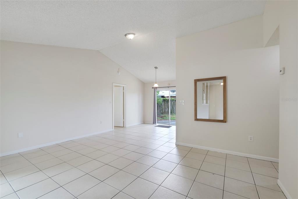 A bright living area with white walls, light tile flooring, and a sliding glass door — 1530 RAVANA DRIVE, ORLANDO, FL