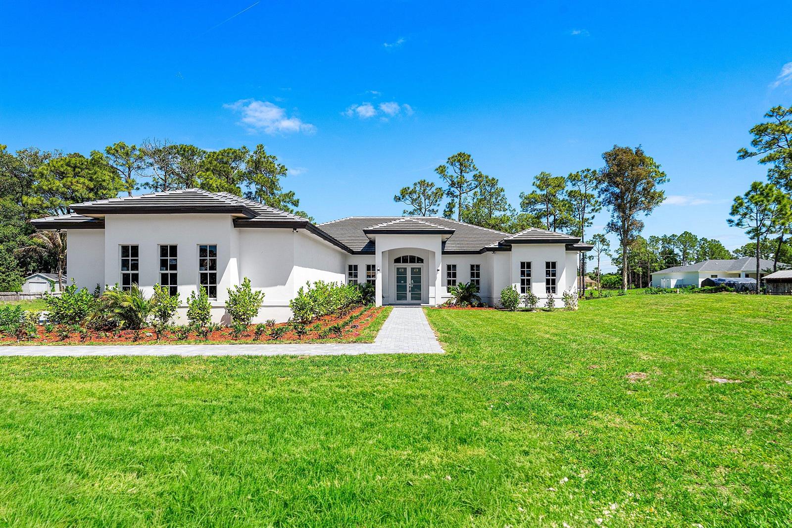 A single-story white house with a dark roof and a paved walkway on a lawn — 15090 Temple Boulevard, FL 33470, FL