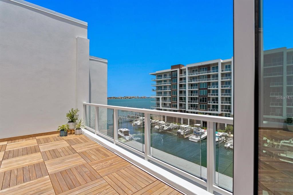 A balcony with wood-tiled flooring overlooks a marina and a multi-story apartment building — 864 N OSCEOLA AVE, CLEARWATER, FL