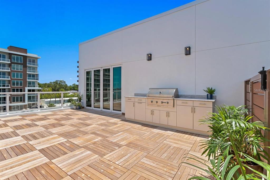 A rooftop terrace features wood-look tile flooring, a built-in outdoor kitchen, and a glass railing — 864 N OSCEOLA AVE, CLEARWATER, FL