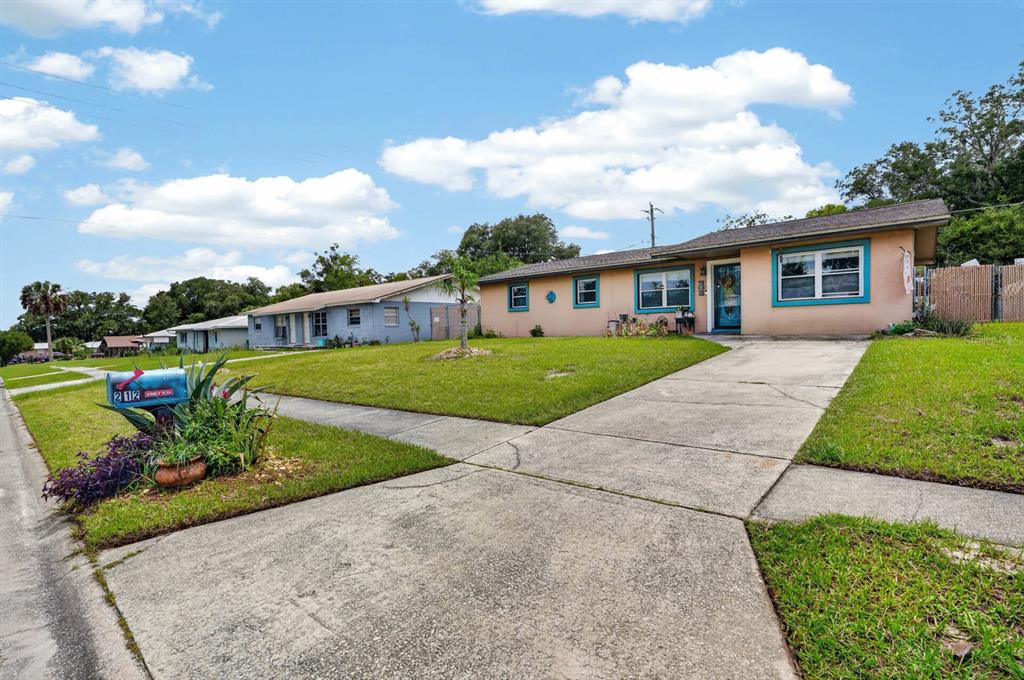 A single-story peach-colored house with blue trim and a concrete driveway under a cloudy sky — 212 MIMOSA DRIVE, PALATKA, FL
