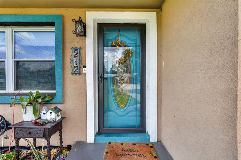 The exterior front entrance features a turquoise storm door, a house number sign, and decor — 212 MIMOSA DRIVE, PALATKA, FL