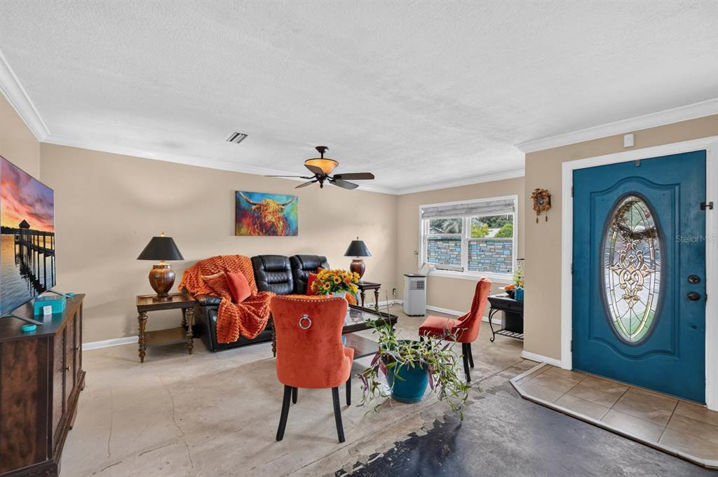 A living room features a blue front door, a black sofa, and orange accent chairs — 212 MIMOSA DRIVE, PALATKA, FL