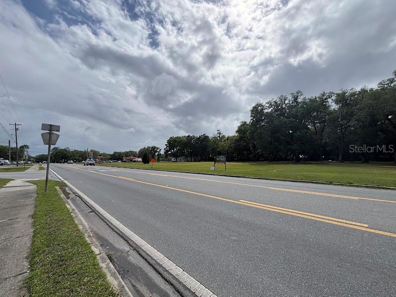 A view of a paved road running alongside a large, open grassy lot with trees — 11471 E HIGHWAY 316, FORT MC COY, FL