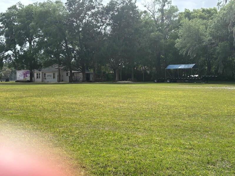 A large grassy field features a small building and a trailer with a blue canopy — 11471 E HIGHWAY 316, FORT MC COY, FL