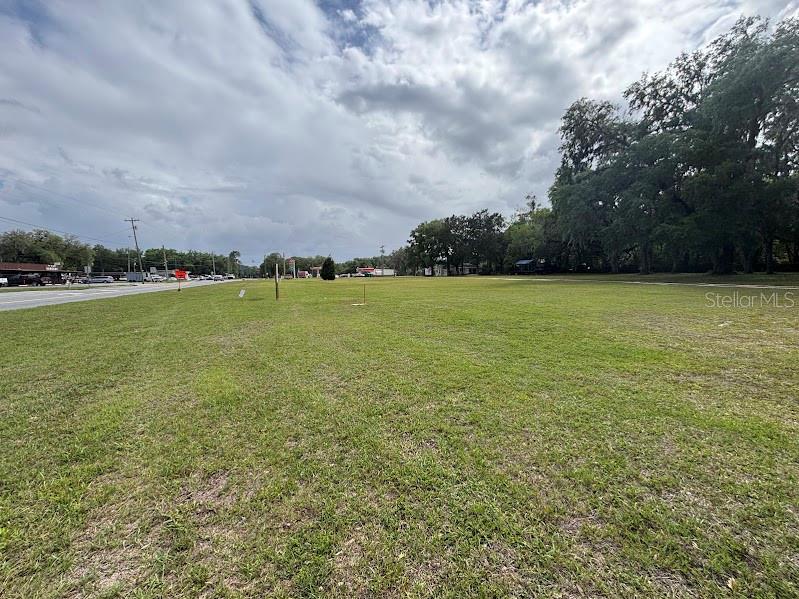 A large, flat, grassy vacant lot sits beside a road under a cloudy sky — 11471 E HIGHWAY 316, FORT MC COY, FL