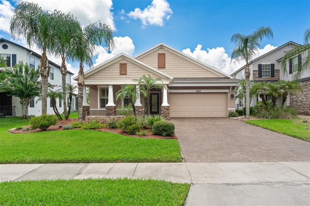 A single-story suburban house with a tan facade, stone accents, and a paved driveway — 1465 BALSAM WILLOW TRAIL, ORLANDO, FL