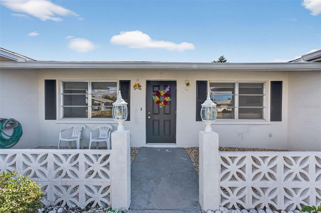 The exterior of a single-story house features a front door, two windows, and decorative blocks — 1735 LORALIN DRIVE, ENGLEWOOD, FL