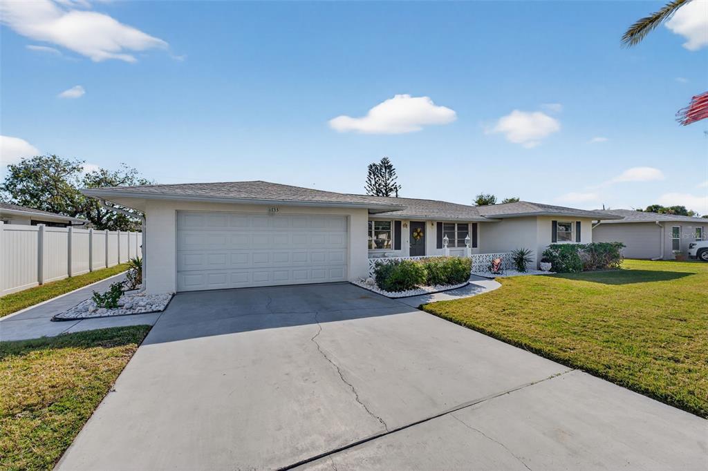A single-story house with a white garage, gray roof, and a front lawn — 1735 LORALIN DRIVE, ENGLEWOOD, FL