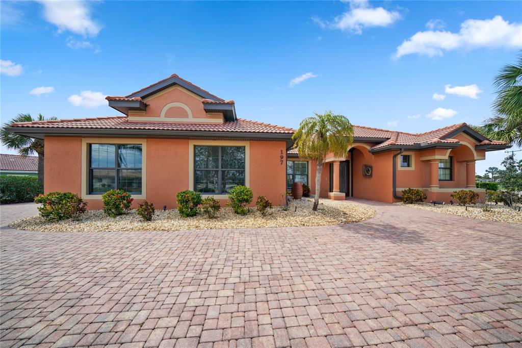 A single-story house with orange stucco walls, a tile roof, and a brick paver driveway — 197 GULFVIEW ROAD, PUNTA GORDA, FL