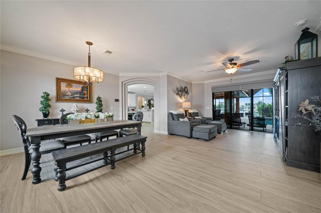 A dining area and living space with wood-look tile floors, a chandelier, and sliding glass doors — 197 GULFVIEW ROAD, PUNTA GORDA, FL