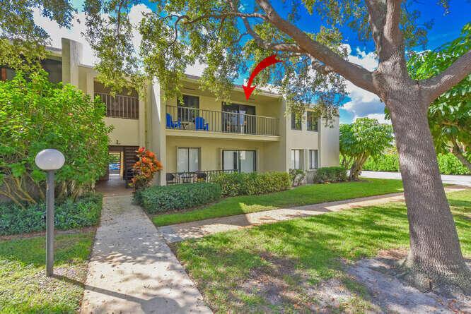 A two-story apartment building features a second-floor balcony with blue chairs and landscaping — 150 Pineview Road # L6, Jupiter FL 33469, JUPITER, FL